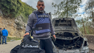 O jornalista Jamal Al-Gharabi, da Al Mayadeen, segura um colete de imprensa ao lado de um carro destruído por um ataque israelense que matou os jornalistas libaneses Fatima Ftouni, repórter da Al Mayadeen, e Mohammed Ftouni, cinegrafista, e Ali Shaib, repórter da Al Manar (Foto: Reuters)
