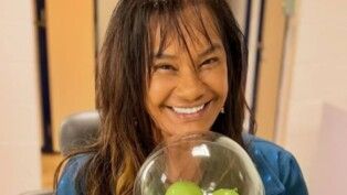 Mulher com franja dando um sorriso para a câmera.