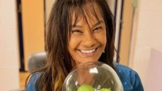 Mulher com franja dando um sorriso para a câmera.