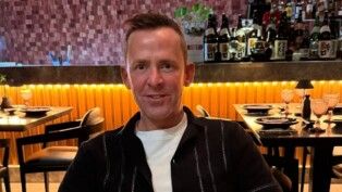 Scott Mills está sentado num restaurante