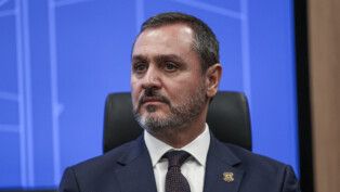 Andrei Rodrigues olha para o lado, à frente de um fundo azul