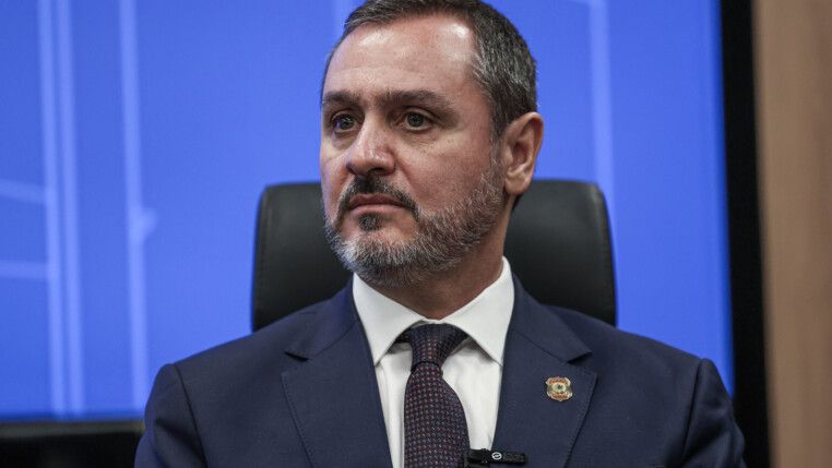 Andrei Rodrigues olha para o lado, à frente de um fundo azul