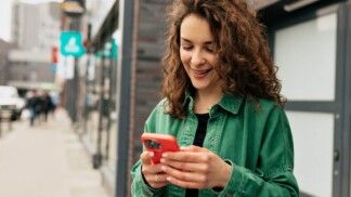 Mulher segurando celular enquanto sorri.