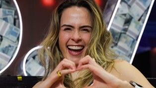 Ana Paula sorri e faz gesto de coração com a mão.