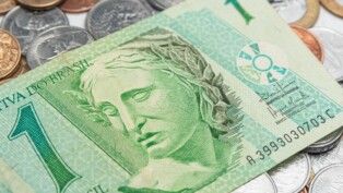 Nota de um real e diversos centavos em uma mesa.