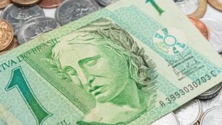 Nota de um real e diversos centavos em uma mesa.