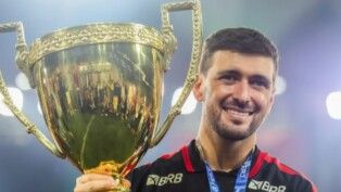 Arrascaeta com uniforme do Flamengo e taça.