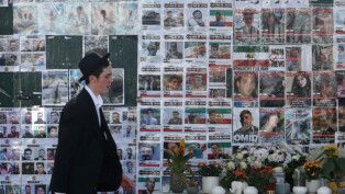 Membro da comunidade judaica passa por muro memorial dedicado às vítimas dos ataques de 7 de outubro em Israel e aos iranianos mortos nos recentes protestos no Irã, em Golders Green, em Londres.