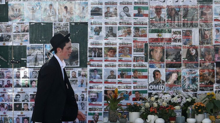 Membro da comunidade judaica passa por muro memorial dedicado às vítimas dos ataques de 7 de outubro em Israel e aos iranianos mortos nos recentes protestos no Irã, em Golders Green, em Londres.