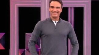 Homem com tricot cinza, suas mãos estão no bolso da calça.