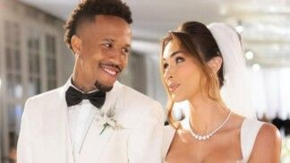 Éder e esposa sorriem um para o outro. Ele usa terno branco. E ela usa vestido de noiva.