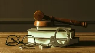 Foto conceitual com livro, algemas e óculos