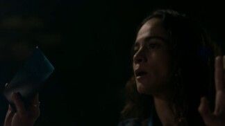 Mulher com a mão para cima enquanto segura celular.