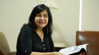 Mariangela Hungria segura livro enquanto está sentada olhando para a câmera