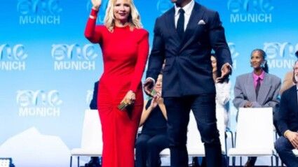 Um homem, Terry Crews, e uma mulher de vestido vermelho, sua esposa, em um palco.