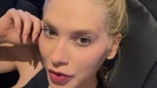 Virginia com o cabelo preso e mão no rosto.