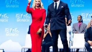 Um homem, Terry Crews, e uma mulher de vestido vermelho, sua esposa, em um palco.