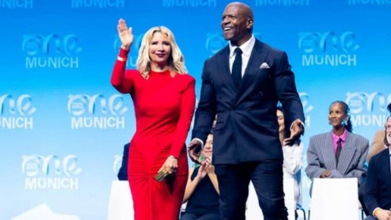 Um homem, Terry Crews, e uma mulher de vestido vermelho, sua esposa, em um palco.
