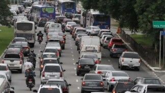 Três vias da rua cheia de carros.