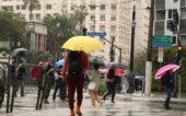 Pessoas com guarda-chuva andando pelas ruas de São Paulo