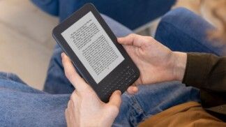 Um homem segurando um Kindle na mão.
