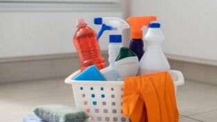 Cesta com diversos produtos de limpeza e um bucha.