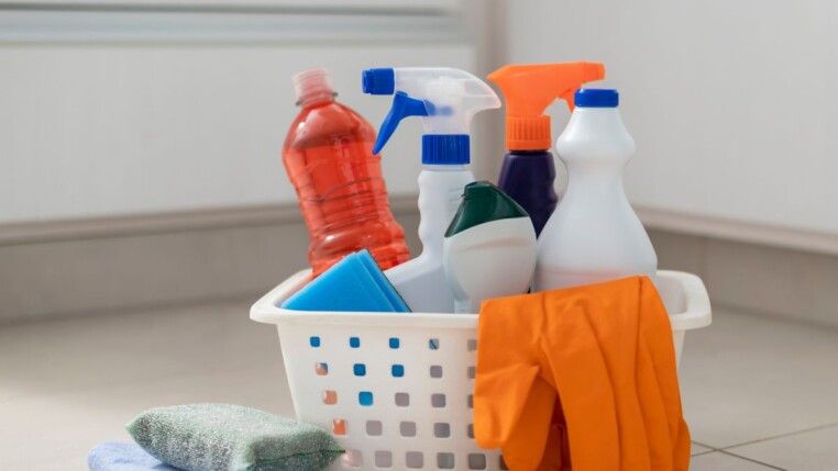 Cesta com diversos produtos de limpeza e um bucha.