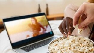 Duas pessoas comendo pipoca assistindo filme.