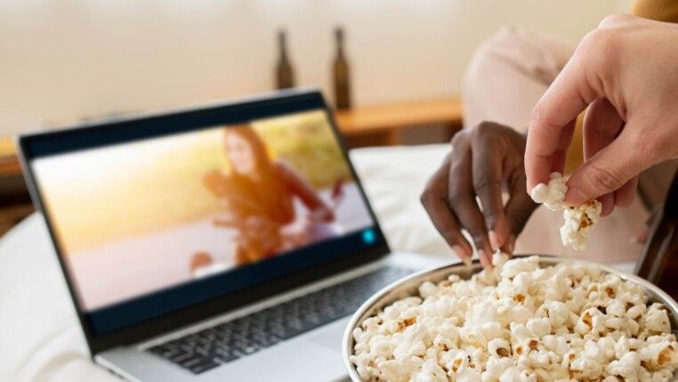 Duas pessoas comendo pipoca assistindo filme.