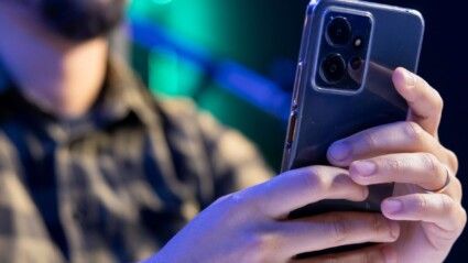 Homem segurando celular.