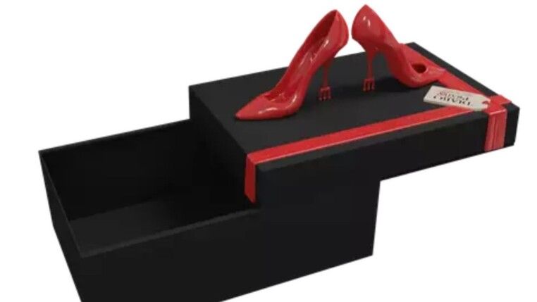 Uma caixa preta com detalhes em vermelho e na tampa há um par de salto vermelho.