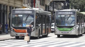 Dois ônibus param diante de um pedestre na faixa