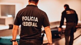 Policial federal caminha em direção à esteira num aeroporto