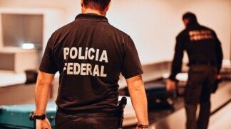 Policial federal caminha em direção à esteira num aeroporto
