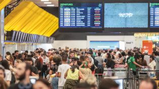 Pessoas circulando pelo saguão de um aeroporto