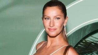 Gisele com brinco prata e vestido, de cabelo preso.