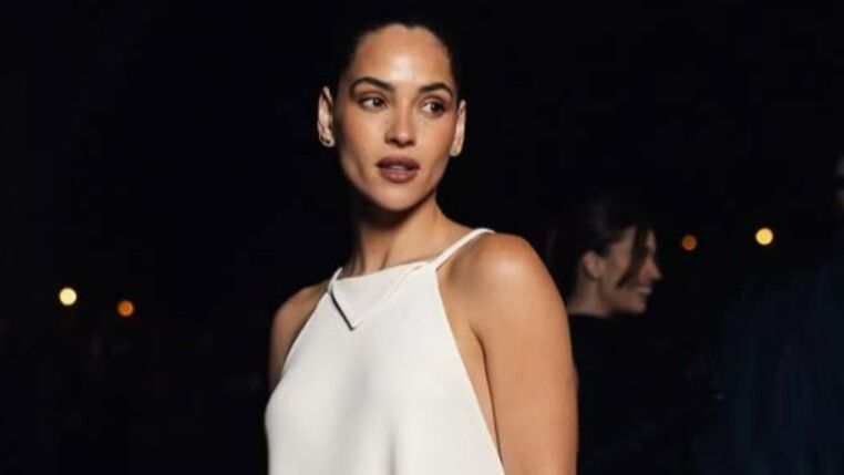 Mulher de roupa branca e coque olhando levemente para o lado.