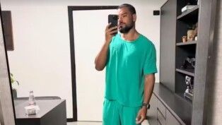 Homem com roupa de enfermagem tirando foto no espelho.