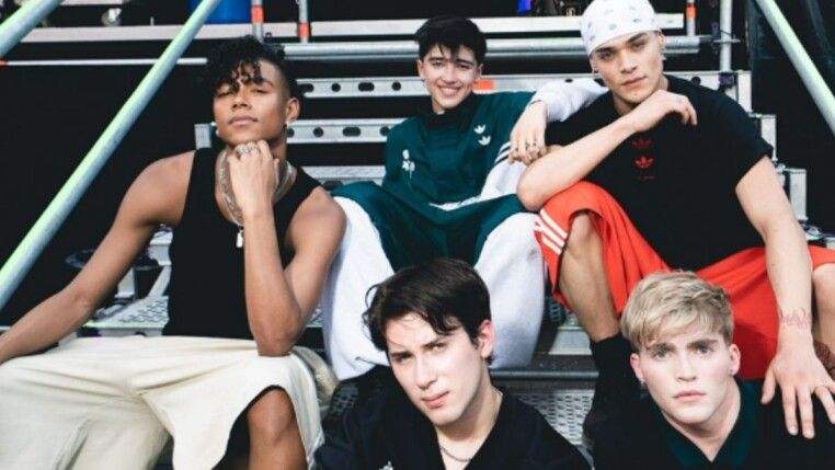 Na foto há 4 homens, eles usam regata e bermuda, outros usam camiseta preta.