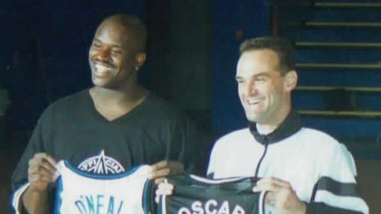 Dois homens seguram uniformes de times de basquete.