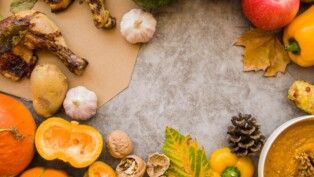 Há diversos alimentos com folhas de árvores em uma mesa.