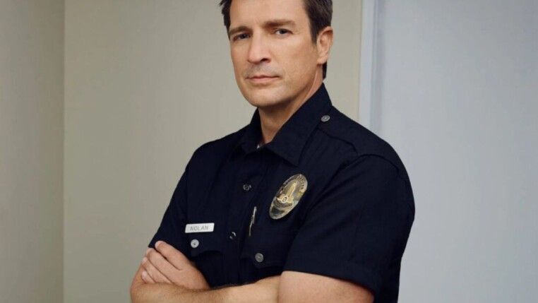 Homem com os braços cruzados e uniforme da polícia.