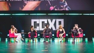 Na foto estão cinco pessoas, elas estão em um palco.