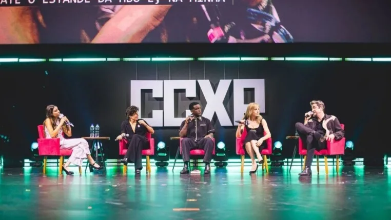 Na foto estão cinco pessoas, elas estão em um palco.