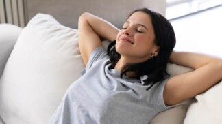 Mulher descansando em um sofá cinza.