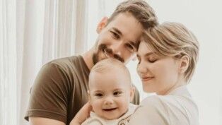 Um homem e uma mulher abraçam uma criança.