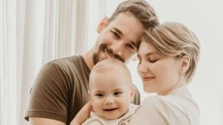 Um homem e uma mulher abraçam uma criança.