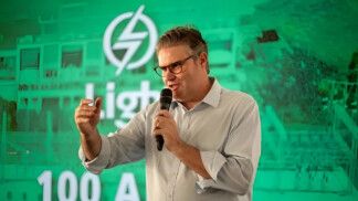 Alexandre Nogueira gesticula enquanto fala ao microfone, à frente de um painel com o logo da Light
