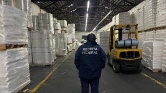 Agente da Receita Federal está de costas para a câmera e de frente para diversos blocos de plástico