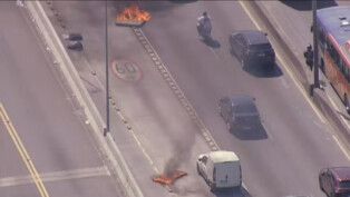 Carros passando na rodovia entre colchões pegando fogo